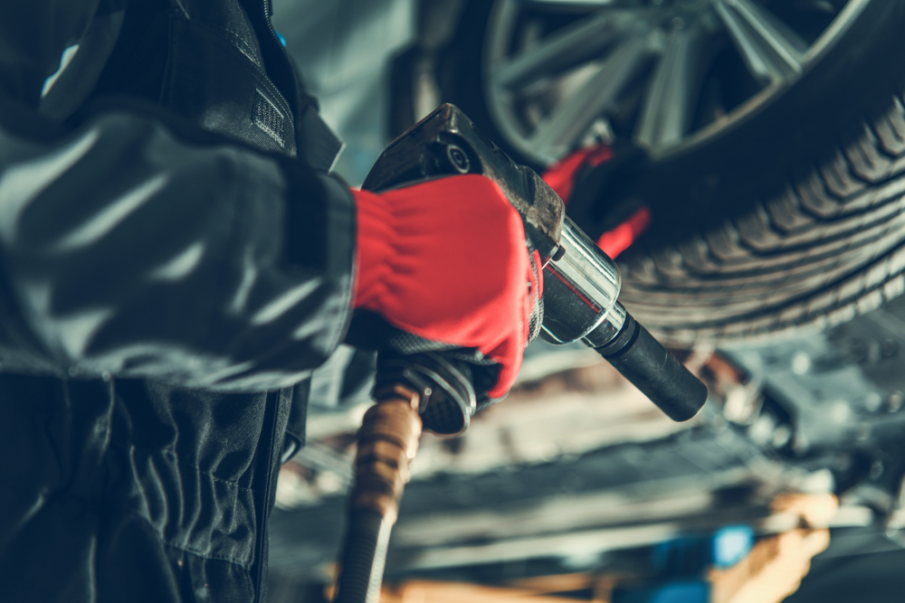 Mechanic using a power tool to service a car tire in a workshop