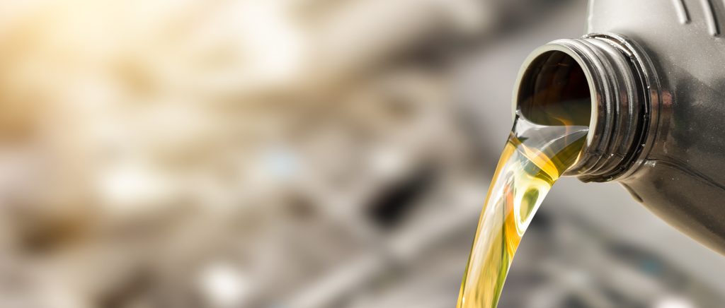Motor oil pouring from a bottle into an engine.