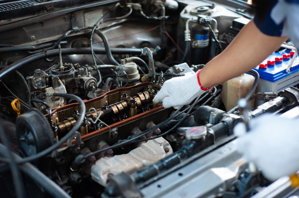 Mechanic inspecting a car engine under the hood.