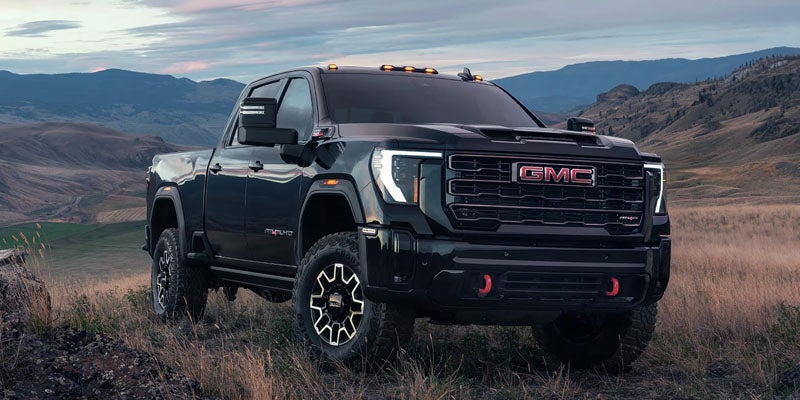 Black GMC pickup truck parked on rugged mountain terrain.
